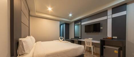 Una camera d'albergo moderna con un letto grande, una scrivania, un televisore e un minibar.