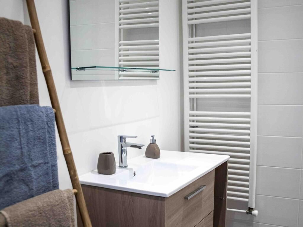 A bathroom with a white sink, a mirror, and a towel rack.