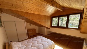 A bedroom with a wooden ceiling, a bed, a dresser, and a window with a view of trees. - Duplex 4-bedroom apartment, 250m from slopes, parking, sleeps 10 - Les Angles (Les Angles)