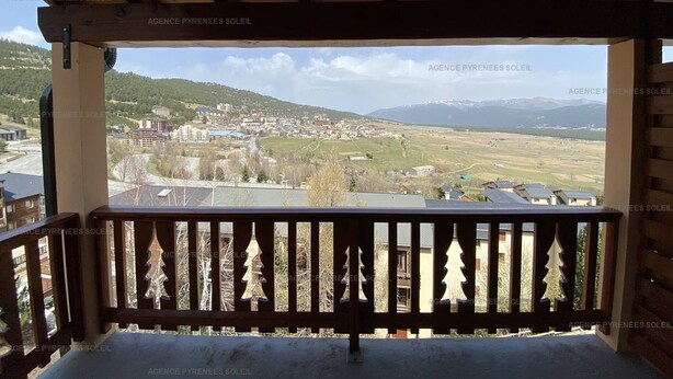 A wooden balcony with a view of a town and mountains. - Duplex 4-bedroom apartment, 250m from slopes, parking, sleeps 10 - Les Angles (Les Angles)
