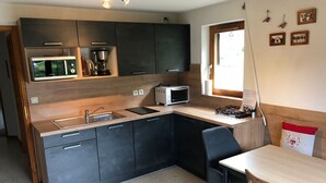A compact kitchen with dark cabinets, a microwave, a toaster, and a sink. - Bright apartment for 6 people with balcony and parking in Châtel (Châtel)