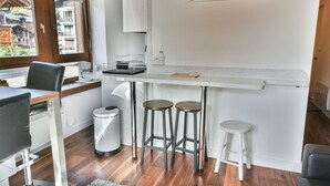 Uma cozinha compacta com área de refeições, uma janela com vista para edifícios e um quadro na parede.