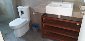 A bathroom with a toilet, sink, and wooden vanity.