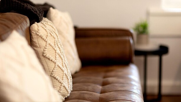 A brown leather sofa with a textured throw blanket and a cushion. - White Rabbit on Jones - Stunning three bedroom classic in the heart of Albury (Albury)