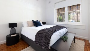 A bedroom with a bed, bedside tables, a bench, a window, and a view of the outside. - White Rabbit on Jones - Stunning three bedroom classic in the heart of Albury (Albury)