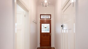 A hallway with a wooden door featuring a stained glass window, white walls, and a wooden floor. - White Rabbit on Jones - Stunning three bedroom classic in the heart of Albury (Albury)