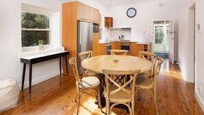 A modern kitchen with wooden cabinets, a central island, and a round dining table surrounded by chairs. - White Rabbit on Jones - Stunning three bedroom classic in the heart of Albury (Albury)
