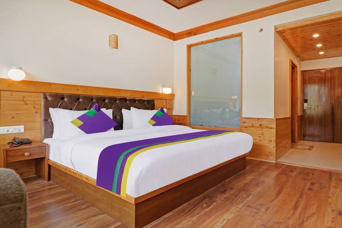 Una cama con estructura de madera, ropa de cama blanca y almohadas coloridas.