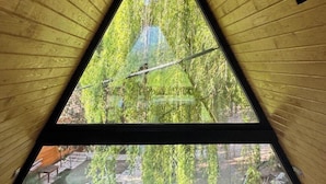 Ein zimmereingedeckter Raum in Dreiecksform mit einem Bett, einem Fenster und einer Glocke.