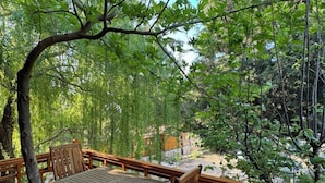 Eine Holzterrasse mit Tisch und Stühlen, umgeben von üppigem Grün und Bäumen.