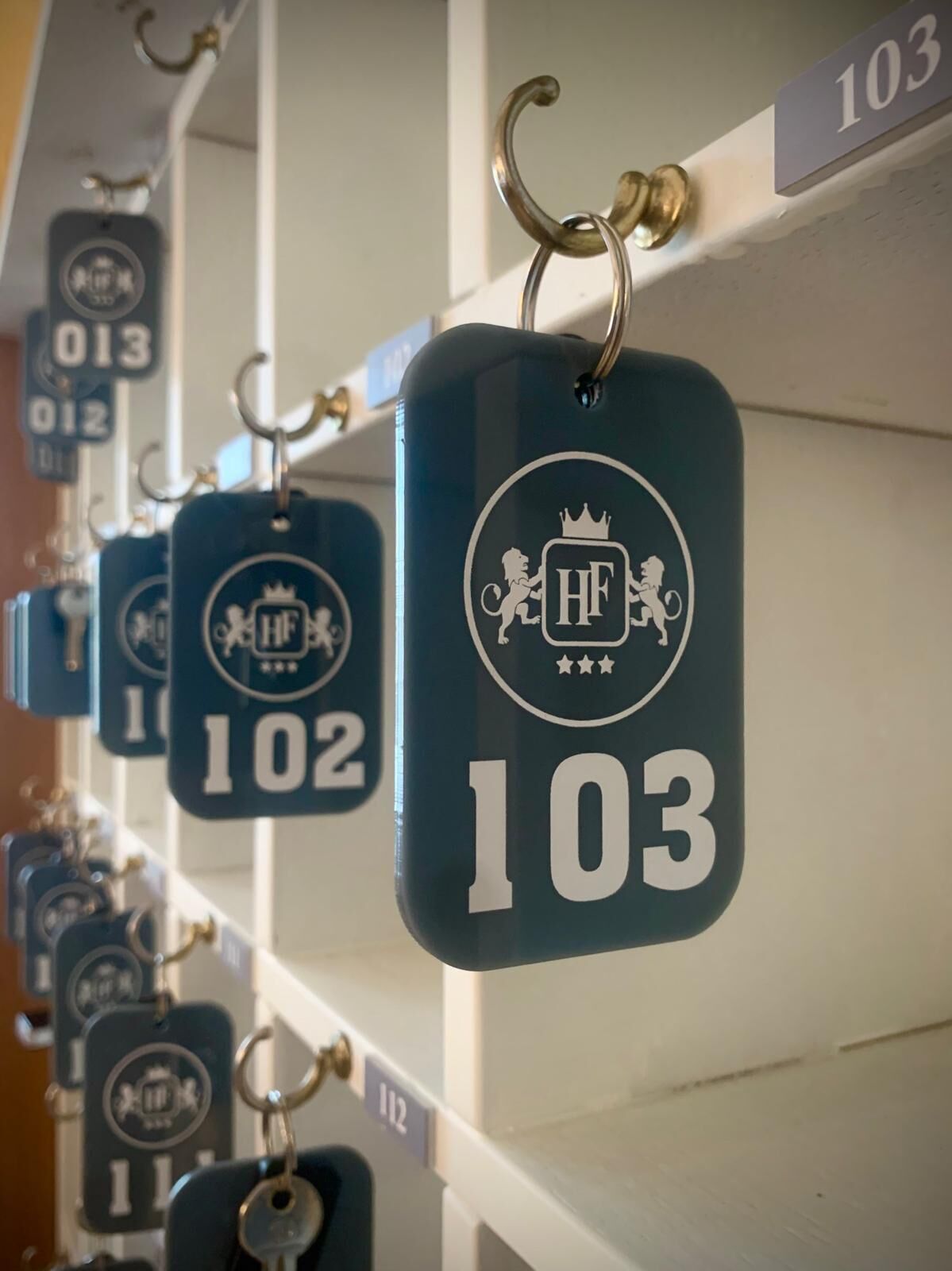 A row of hotel room numbers 102 and 103, each with a keychain and a number tag.