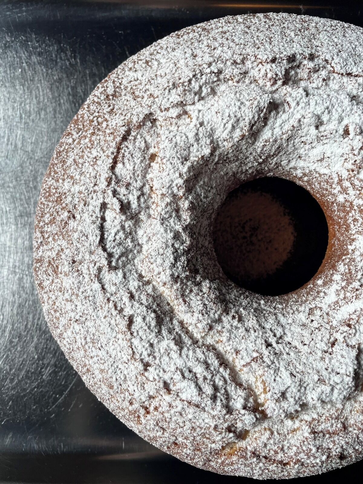 Un gâteau rond recouvert de sucre glace et percé d’un trou au centre.