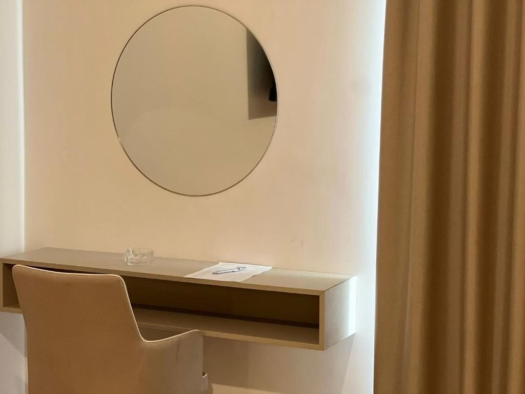 Ein modernes Zimmer mit Schreibtisch, Stuhl und einem großen Spiegel an der Wand.