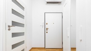 A hallway with a white door, a wall-mounted air conditioner, and a wooden floor. - Air-conditioned Apartment in the Center | Separate Bedroom (Warszawa)