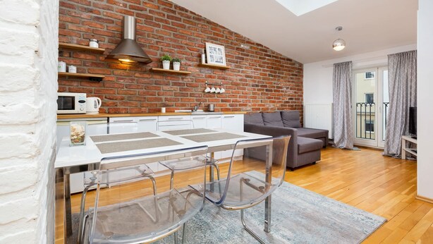 A modern kitchen with a brick wall, white cabinets, and a skylight. - Air-conditioned Apartment in the Center | Separate Bedroom (Warszawa)