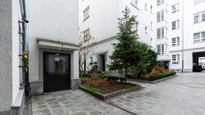 A courtyard with a small tree, a planter with flowers, and a building entrance. - Air-conditioned Apartment in the Center | Separate Bedroom (Warszawa)