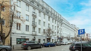 A multi-story building with a white facade, several balconies, and a parking sign indicating a parking area. - Air-conditioned Apartment in the Center | Separate Bedroom (Warszawa)