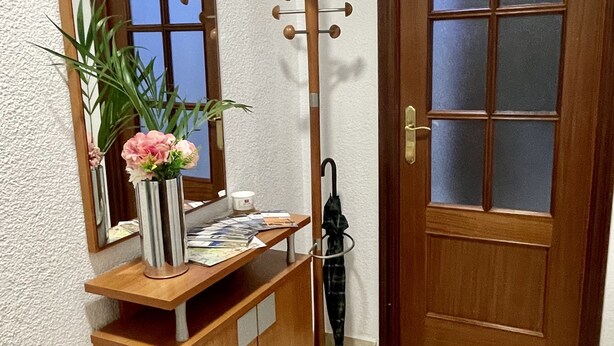A wooden cabinet with a mirror, a vase with flowers, and a coat rack with an umbrella. - Studio in the center of Granada (Granada)