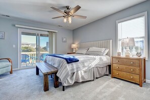 A bedroom with a bed, a ceiling fan, a bench, a dresser, and a window with blinds. - Topsl Turvy, Turtle Cove 209 | Surf City, NC | Community Pool & Beach Access (Surf City)