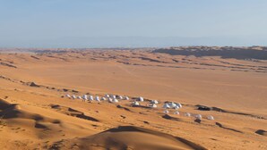 A desert landscape with numerous white dome-shaped structures scattered across the sand dunes. - Luxury Desert Camp Oman (Bidiya)