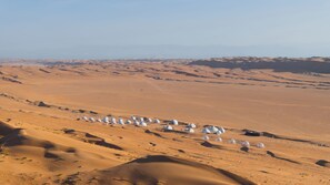 A desert landscape with numerous white dome-shaped structures scattered across the sand dunes. - Luxury Desert Camp Oman (Bidiya)