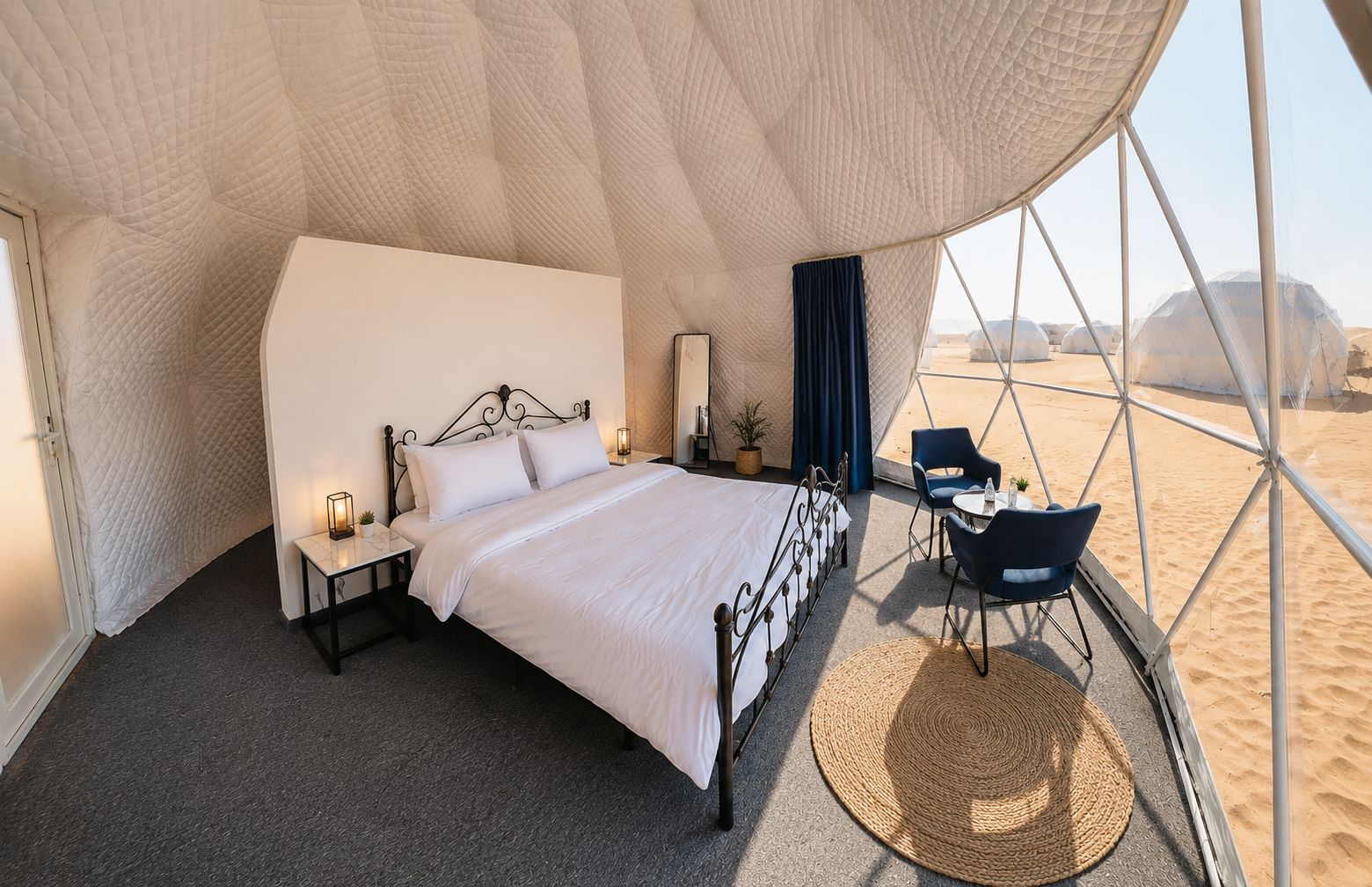 A tent-style room with a bed, bedside tables, and a view of the desert.