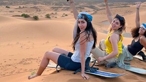 Three people sitting on sand dunes with a sunset in the background. - Luxury Desert Camp Oman (Bidiya)