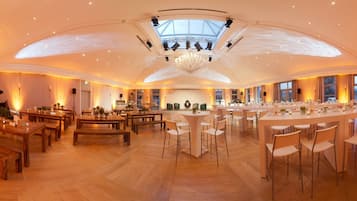 A spacious hotel lobby with a high ceiling, wooden flooring, and a central bar area.