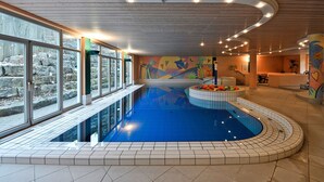 An indoor swimming pool with a mural, large windows, and a wooden ceiling. - HerzogsPark Studios & Apartments (Herzogenaurach)