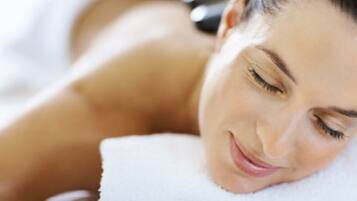 A person lying down with a white towel, suggesting a spa or relaxation setting.