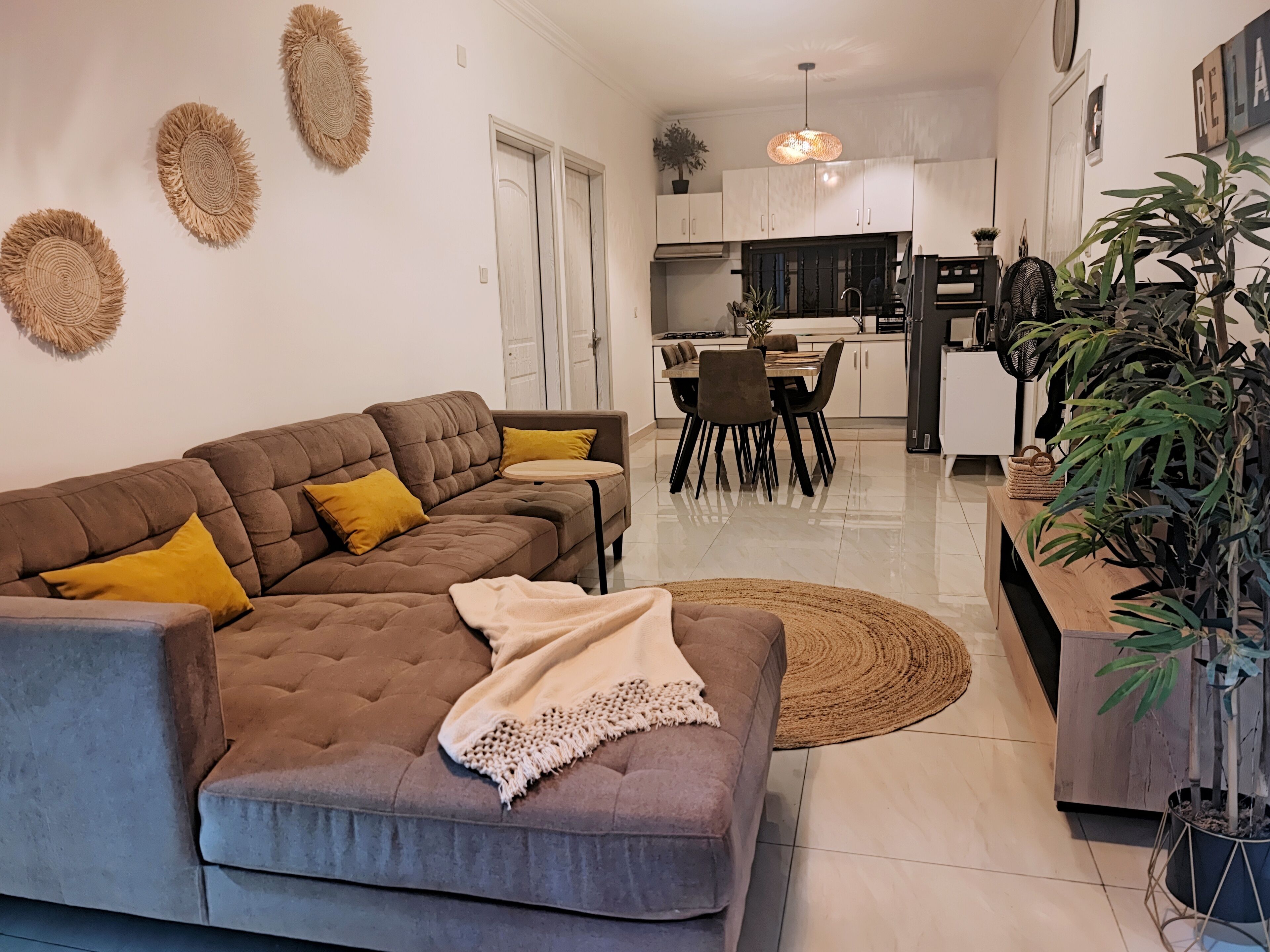 A modern living room with a sectional sofa, a dining area, and a kitchen in the background.