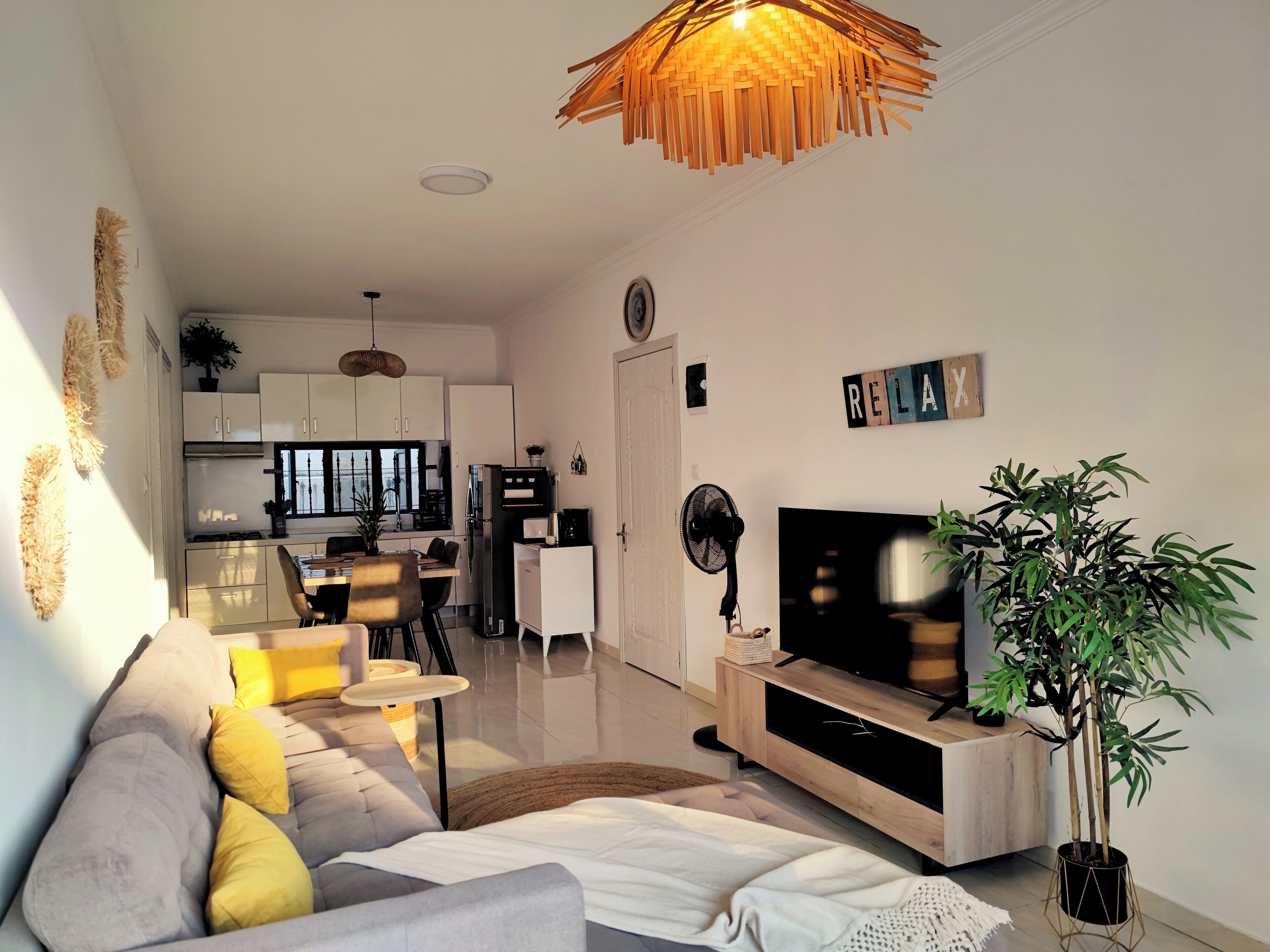 Un salón moderno con un sofá, televisión y un comedor al fondo.