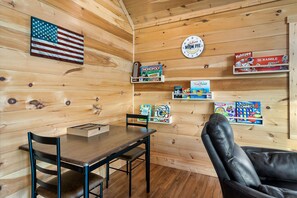 Ein Holzinterieur mit einem Tisch, Stühlen und Regalen voller Gesellschaftsspiele.