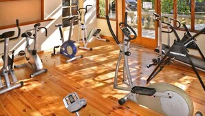 Et fitnesscenter med forskellig træningsudstyr, herunder løbebånd, spinningcykler og en crosstrainer.