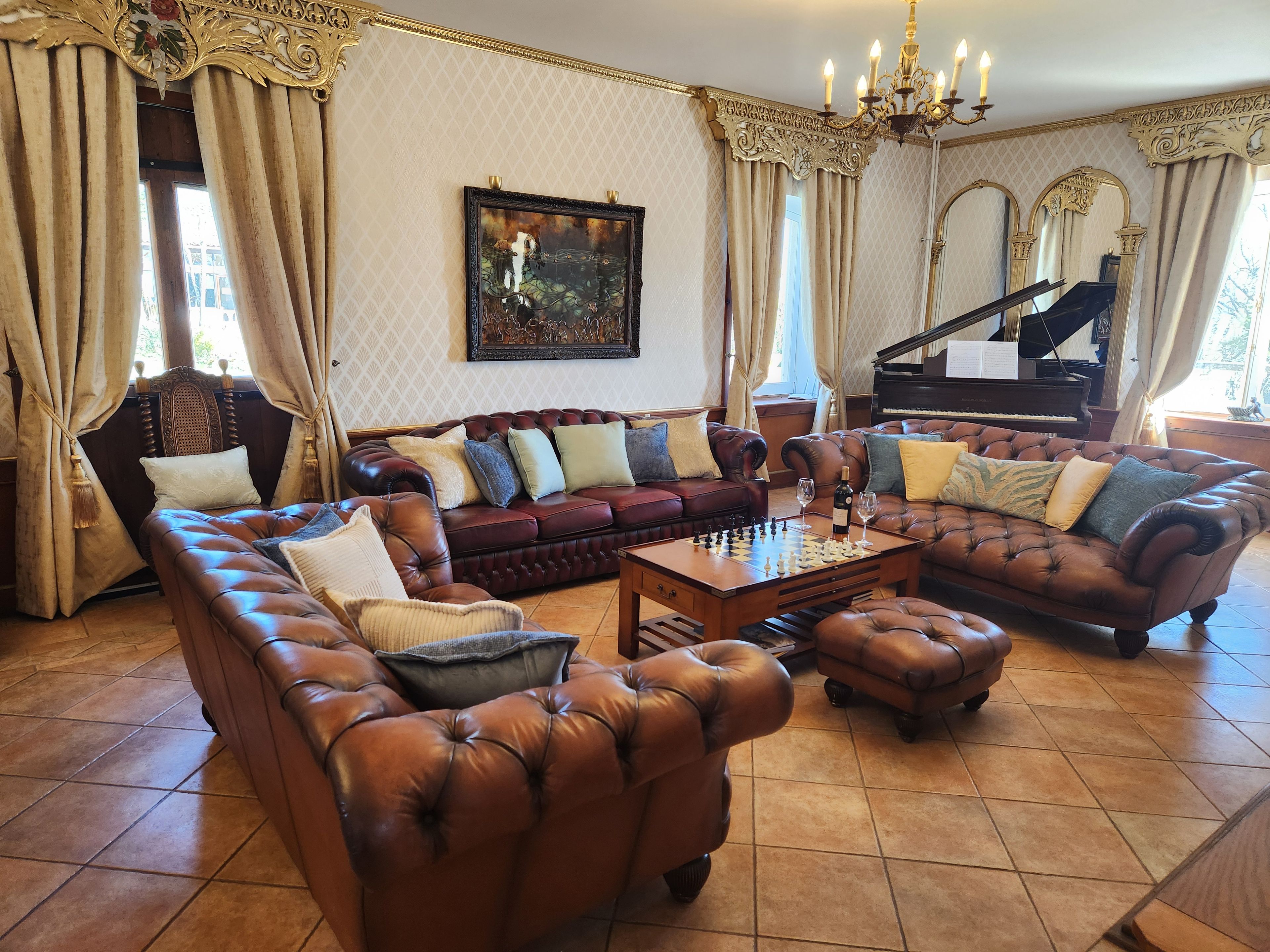 A luxurious living room with a grand piano, leather sofas, and a chessboard.