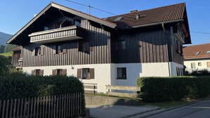 A two-story wooden house with a balcony, a white lower section, and a brown upper section.