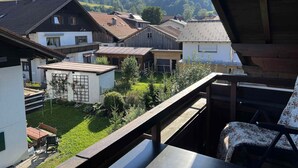 A residential area with houses, a wooden deck, and a view of a forested hill.
