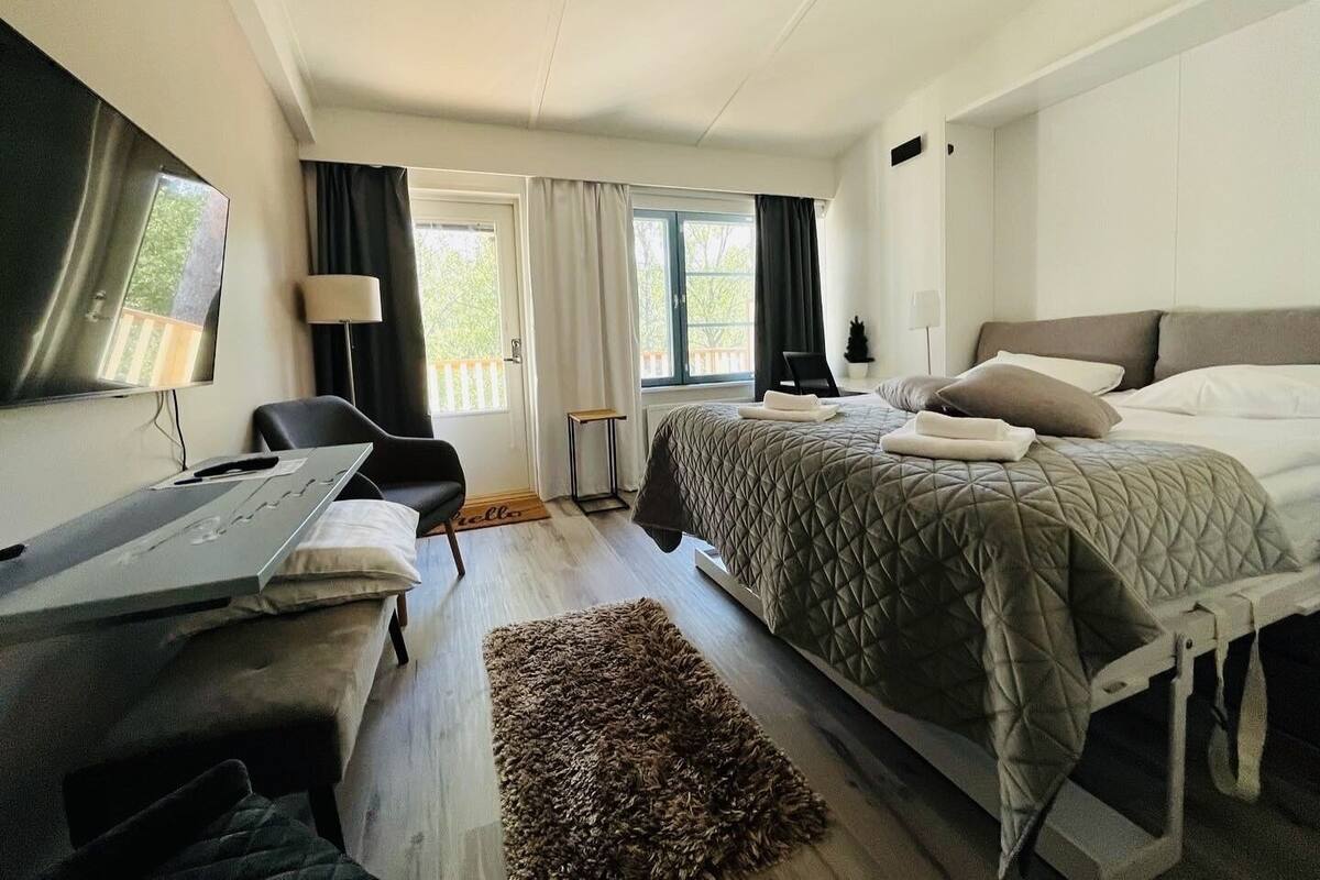 Ett hotellrum med en säng, ett skrivbord, en stol och utsikt över omgivningarna.