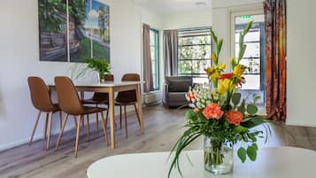 Una zona de dinar moderna amb una taula blanca i cadires marrons, un ram de flors i un quadre a la paret.