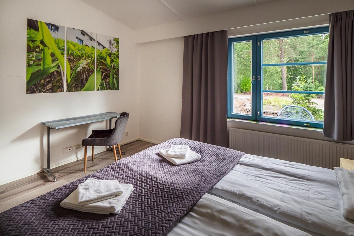 A hotel room with a bed, a desk, a chair, and a large window with curtains.