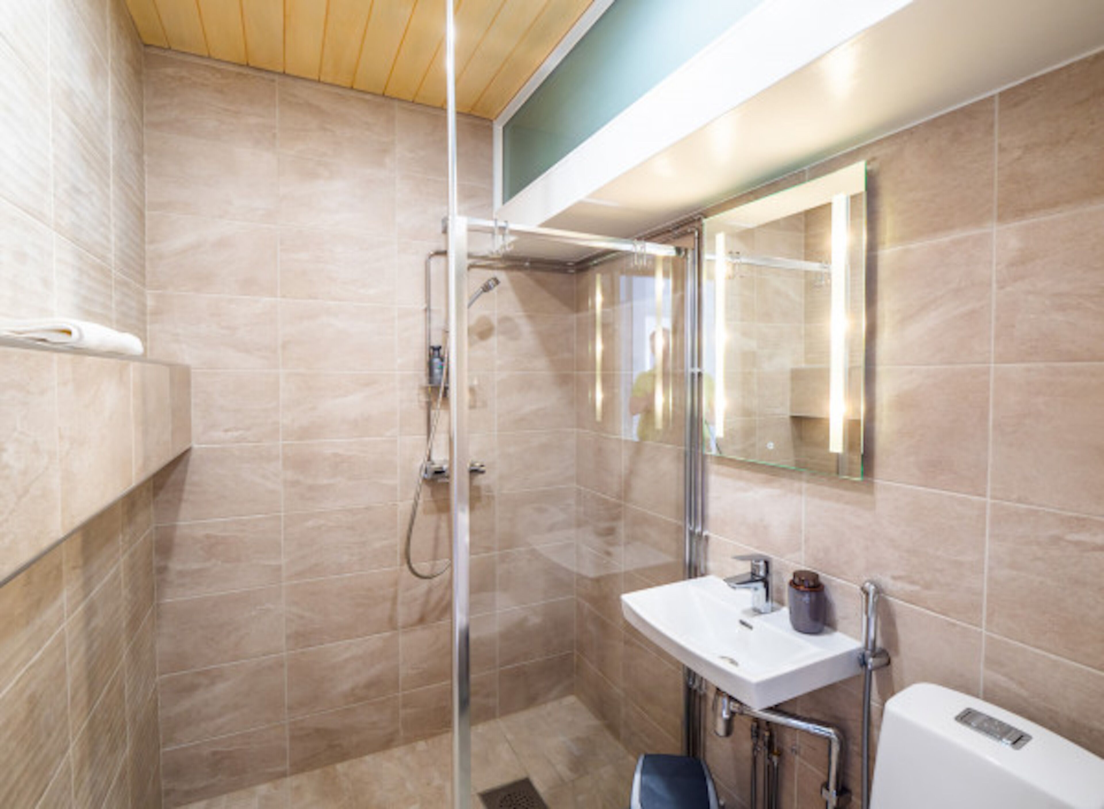 A modern bathroom with a glass-enclosed shower, a white sink, and a mirror above it.