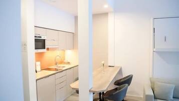 Una cocina moderna con armarios blancos, una mesa de comedor de madera y dos taburetes de bar.