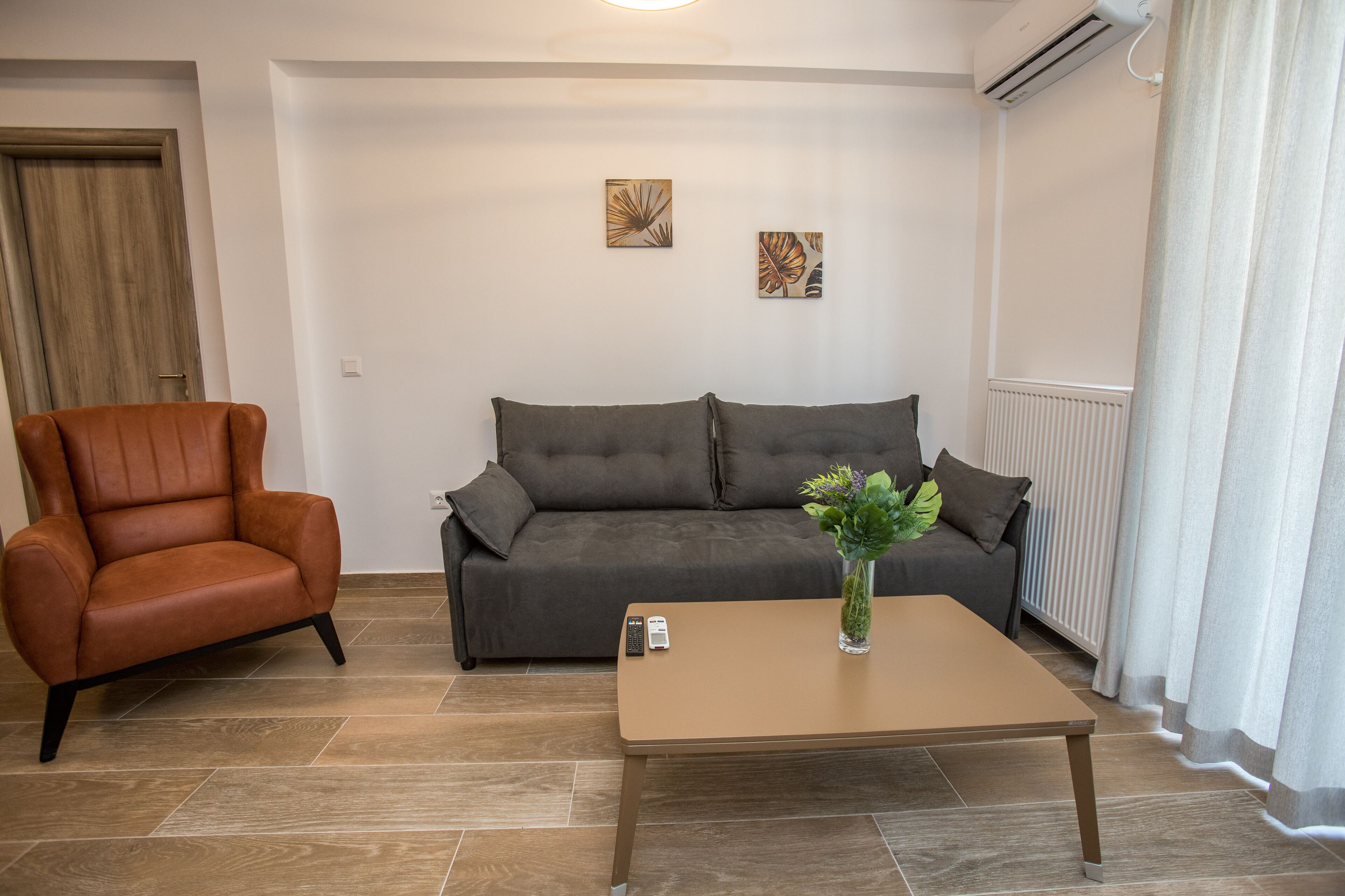 Ein Wohnzimmer mit einem braunen Ledersessel, einem grauen Sofa und einem Holztisch.