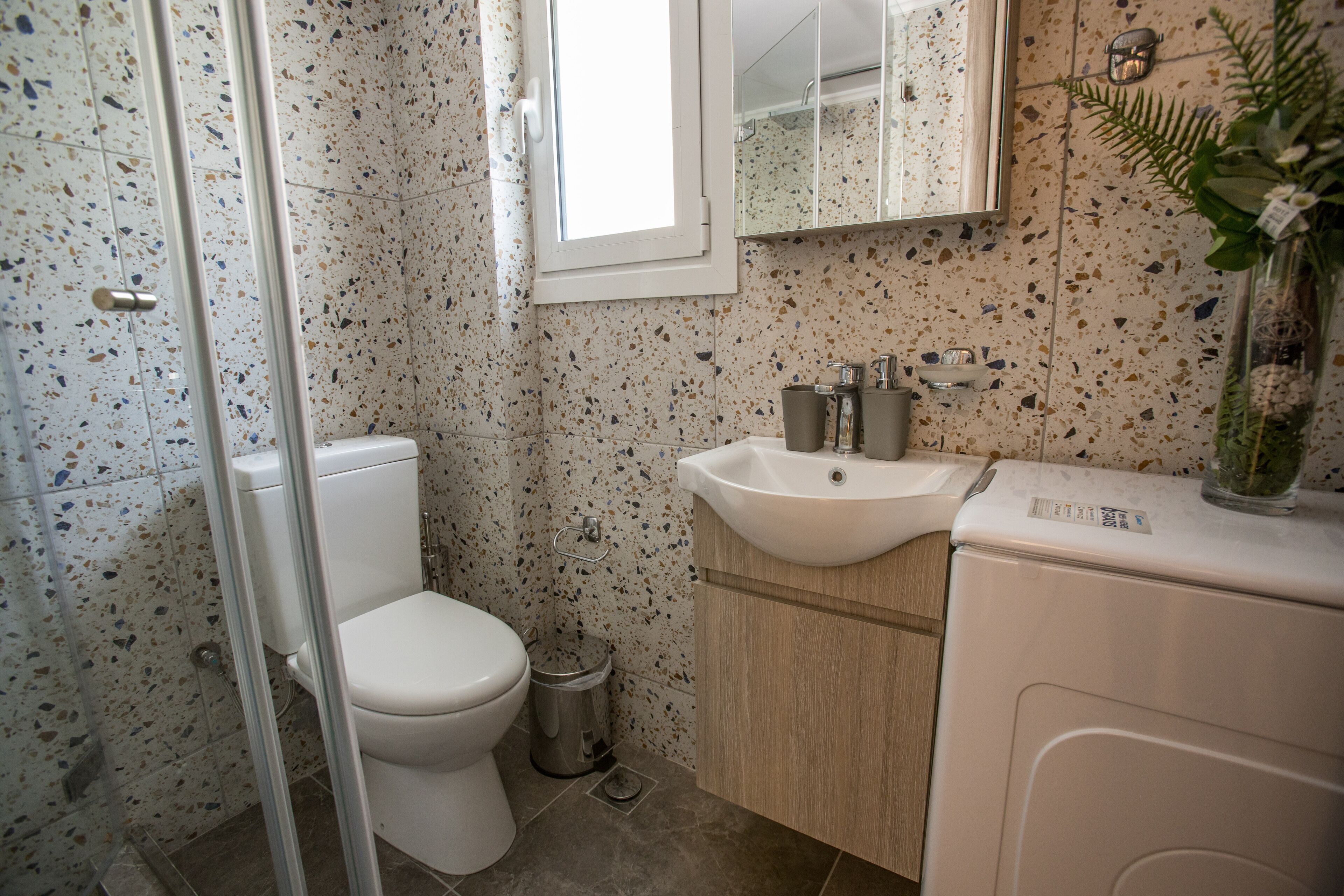 Een badkamer met een wit toilet, een wastafel en een spiegel.