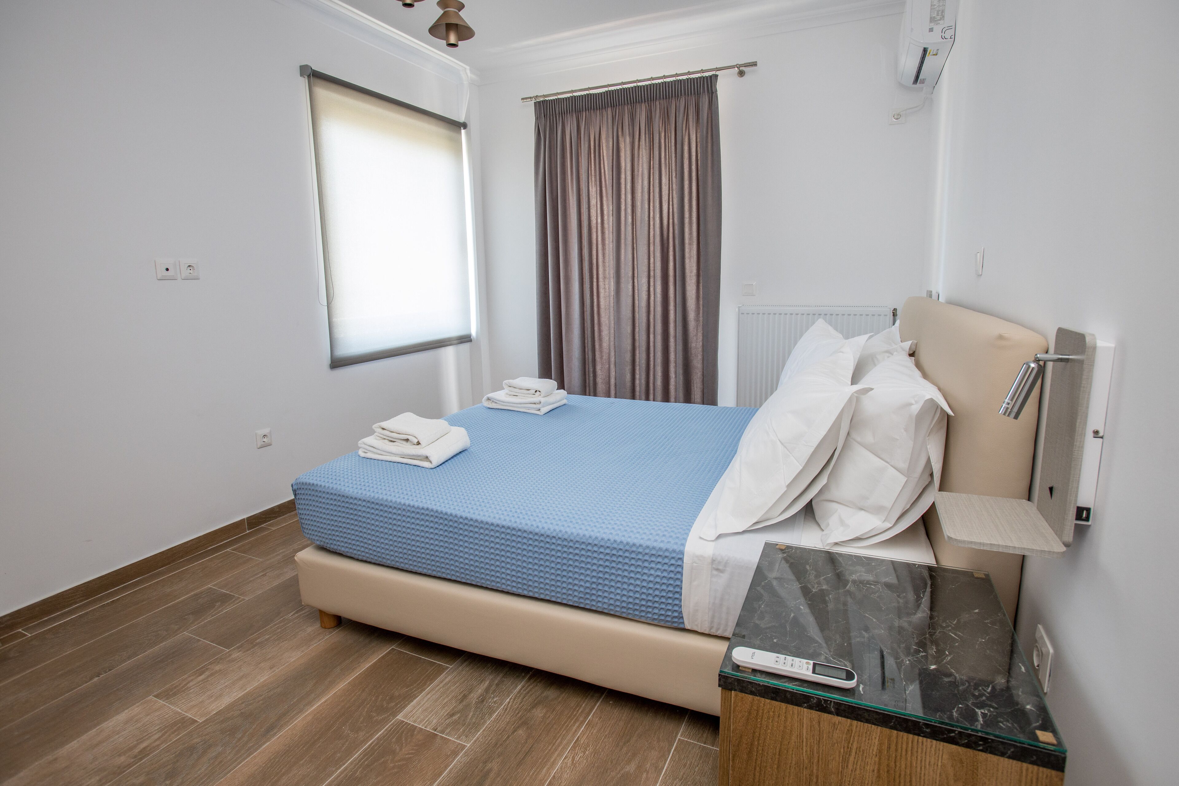 Una camera da letto con un letto, un comodino, una finestra e una tenda.
