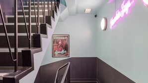 A staircase with metal railings leading to a landing. A neon sign on the wall reads "Dancing on the Floor." - West End 2-Bed · Soho · Sleeps 6 (London)