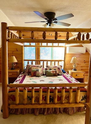 A four-poster bed with a wooden frame and a ceiling fan above.