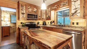 Una cocina con armarios de madera, una isla central, microondas, estufa y lavavajillas.