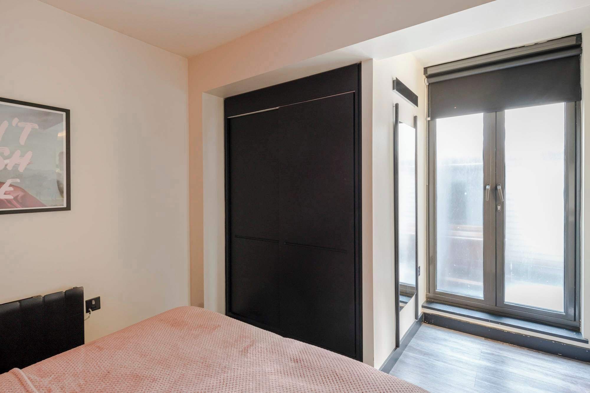 Un dormitorio con cama, una puerta negra y un ventanal con vistas.