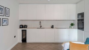 A modern kitchen with white cabinets, a built-in oven, and a coffee maker. - Stunning 2-Bed Mews House w/ AC near Regent's Park (London)